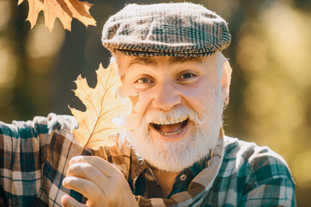 Senior citizen stroll in a park in autumn. Old man alone in autumn park. Elderly old man on autumn background - face portrait close up.の写真素材