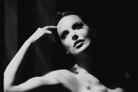 Sensual girl. Portrait of beautiful woman model looking seductive and sensual. Beauty face with dramatic studio light isolated on black.の写真素材