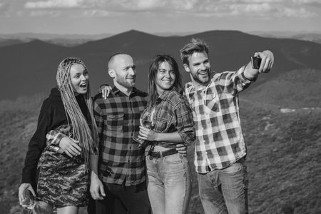 Group of friends taking a selfie in the mountains. Group of hikers takes photo in nature. Camping together is fun, friendship. Students on summer vacation laughing and talking.の写真素材