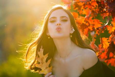 Autumn portrait of cheerful woman with yellow maple leaves. Portrait of beauty girl with autumn leafs on foliage. Close up portrait of a beautiful girl near autumn leaves. Romantic tenderness woman.の写真素材