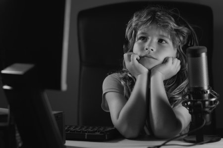 Child with pc computer at night. School, study, online learning concept. Overuse and addiction kids from gadgets.の写真素材