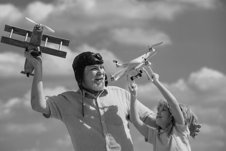 Grandfather and son with plane and quad copter drone over blue sky. Men generation granddad and...