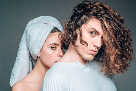 Beautiful passionate couple. Couple In Love. Young heterosexual couple embracing on grey background. I Love You. Lifestyle. Romantic evening of a young couple. A towel on her head.の写真素材
