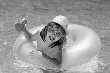 Boy kid in pool drinking cocktail. Happy lifestyle kids. Water toy, healthy outdoor activity for...
