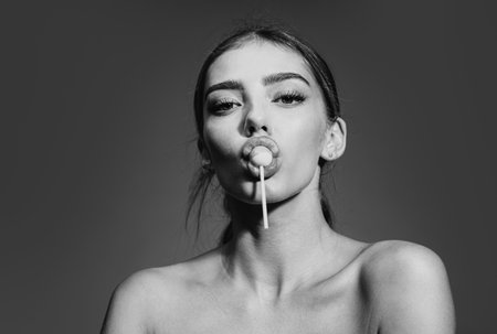 Sexy woman face. Close-up portrait of nice alluring charming glamorous sweet sexy lady with lollipop in mouth. Sucking licking red sweet candy.の写真素材