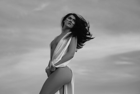 Woman in white dress outdoors on sky. Fashion outdoor photo of gorgeous sensual woman in elegant dress clothes. Beauty and fashion girl.の写真素材