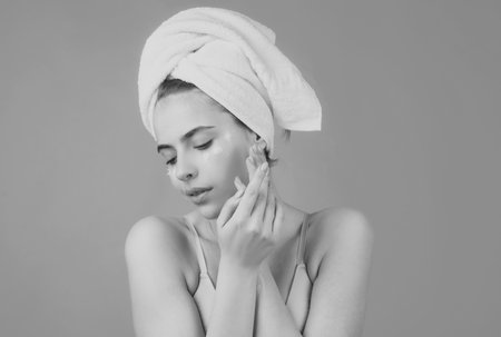 Beauty face portrait. Spa therapy, beautiful woman in towel takes care of skin, isolated on pink.の写真素材