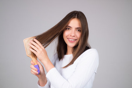Beautiful woman combing her hair in studio.の写真素材