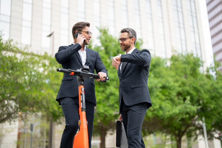 Caucasian employee on urban background office building texting messages on mobile phone. Business man standing a formal suit using smartphone cellphone outdoors.の写真素材