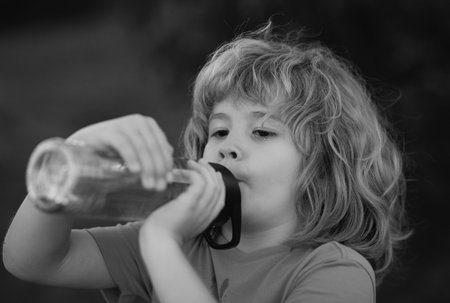 Child drinking water from bottle outdoor in park. Kid drinking.の写真素材