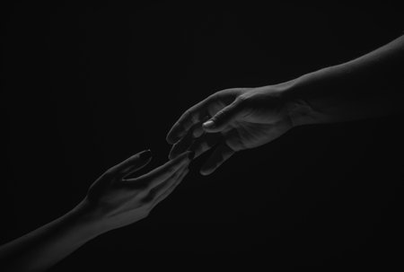 Two hands. Helping hand to a friend. Rescue or helping gesture of hands. Concept of salvation. Hands of two people at the time of rescue, help. Isolated on black background.の写真素材