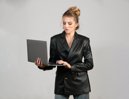 Sexy serious woman using laptop computer over isolated background.の写真素材