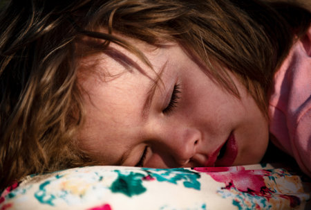 Close up face of baby lying in bed and sleeping. Child sleep quietly calmly on bed at home. Baby child sleeping on the bed lying on his back under the blanket, healthy sleep.の写真素材