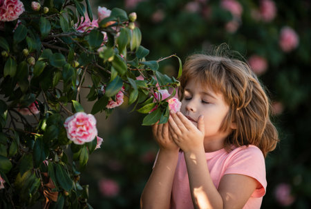 Portrait of a sweet little child enjoying flowers aroma, having fun in spring park. Little kid on meadow with wild flower. Happy child outdoors in spring field.の写真素材