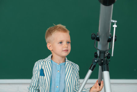 Pupil school kid with telescope learning astronomy lesson at school.の写真素材