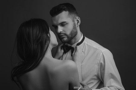 Passionate couple, romantic lovers. Woman holds mans bowtie, bow tie. Sexy elegant people in tender passion.の写真素材
