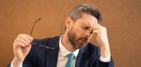 Overworked man feeling migraine head strain. Tired bored man has office syndrome. Exhausted man work on laptop struggle with migraine or headache. Office worker, manager freelancer having a headache.の写真素材