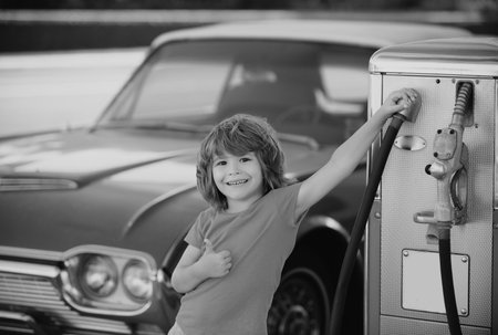 Child at gas station against red retro automobile.の写真素材