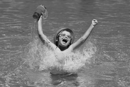 Cute child in hat and sunglasses swim in pool with blue water background. Happy summer holidays. Kid...