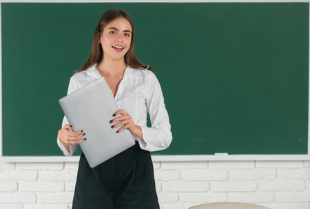 Portrait of female university student holding laptop at school or university. Girl student with pc technology, distance learning.の写真素材