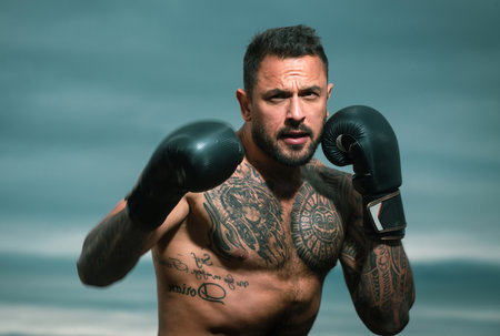 Portrait of tough male boxer posing in boxing gloves. Professional fighter ready for boxing match....