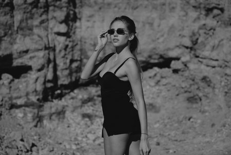 Fashion woman in trendy sunglasses and fashion black dress outdoor. Attractive woman in fashion outfit outside. Outdoor fashion photo of young beautiful lady enjoying summer.の写真素材