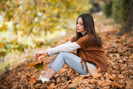 Autumn woman with fall yellow maple leaf, outdoor portrait. Beautiful model with autumn leaves, fall...