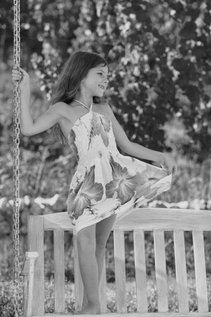 Child swing on backyard. Kid playing oudoor. Happy cute little girl swinging and having fun healthy summer vacation activity. Active summer leisure for kids.の写真素材