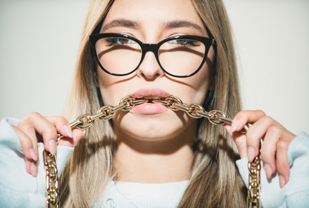 Beautiful girl. Sensual woman close up portrait with golden chain in mouth.の写真素材