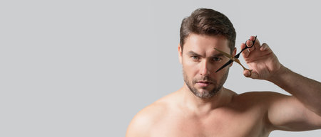 Banner of men hairstyle, haircut. Guy with scissors. Mens haircare, beauty barber concept. Portrait of unshaven man, with scissors. Man cut hair with scissors. Hair styling and cut with scissors.の写真素材