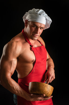 Sexy cooking man in apron. Muscular chef with bowl. Sports diet.の写真素材