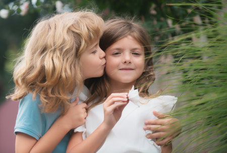 Hugging and kissing kids couple. Little lovely children outdoor. Children in summer park, close up face. Kids love together.の写真素材