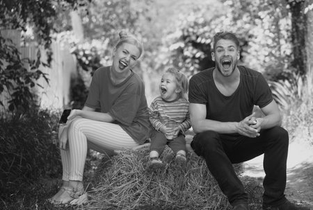 Happy young family of three having fun together launching. Cheerful funny parents playing with son outdoor. Father mother and child playing together.の写真素材