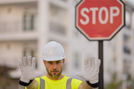 Worker in uniform gesturing stop. Serious builder with stop road sign. Builder with stop gesture, no...