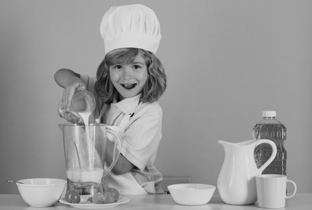 Cooking children. Chef kid boy making fresh vegetables for healthy eat. Portrait of little child in...