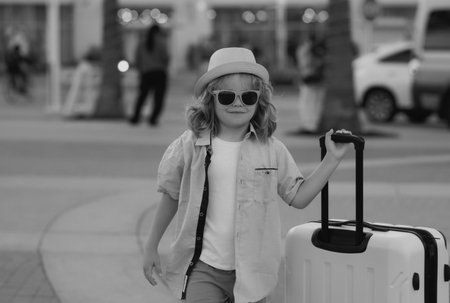 Child boy going on summer trip, holding luggage travel bag outdoor.の写真素材