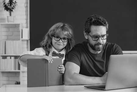 Teacher helping child student pupil from elementary school in classroom. Teacher and pupil boy learning in the classroom.の写真素材