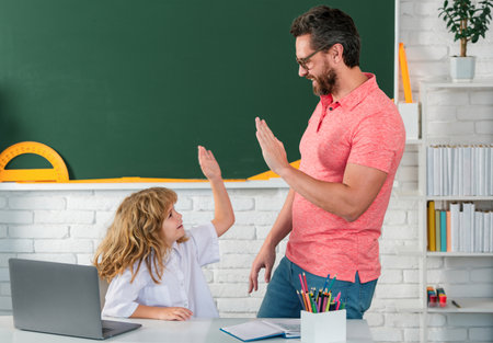 Kid boy learning with teacher. Funny little boy study with father in class on blackboard. Pupil of primary elementary school has lesson. Kid boy with teacher learn english language or mathematics.の写真素材