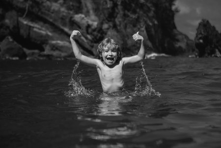 Amazed excited kid im sea water. Funny kid playing on beach.の写真素材