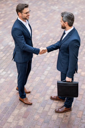 Successful teamwork. Business people shaking hands. Business men in suit shaking hands outdoors. Business idea. Business man relationships with client. Collaboration and teamwork partnership.の写真素材