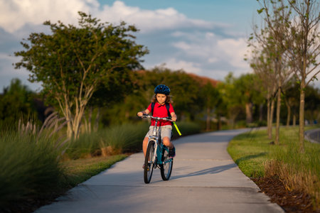 Sporty kid riding bike on a park. Child in safety helmet riding bicycle. Kid learns to ride a bike. Kids on bicycle. Happy child in helmet cycling outdoor. Sports leisure with kids.の写真素材
