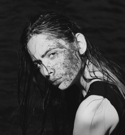 Portrait of beautiful young woman with with a dirty mud face. Outdoor portrait of a cute girl. Happy...