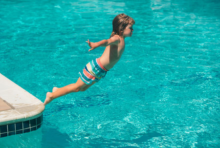 Kid at aquapark. Child jumping into water on summer vacation. Swimming on summer camp.の写真素材