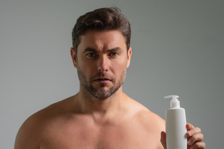 Man with cosmetic beauty products. Beauty man with cosmetic bottle. Natural cosmetics cream for skin care. Spa beauty products. Man advertising cosmetic product. Male model promoting for beauty shop.の写真素材