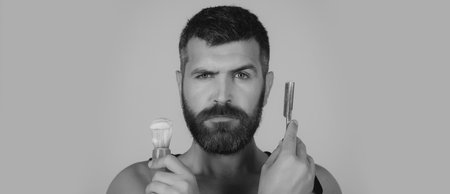 Bearded man shaving with blade razor, unshaved bearded gay. Barber with straight razor, barbershop. Shaving in barber shop. Templates web banner.の写真素材