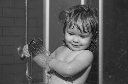 Child having fun to bath. Baby showering. Portrait of kid bathing in a bath with foam.