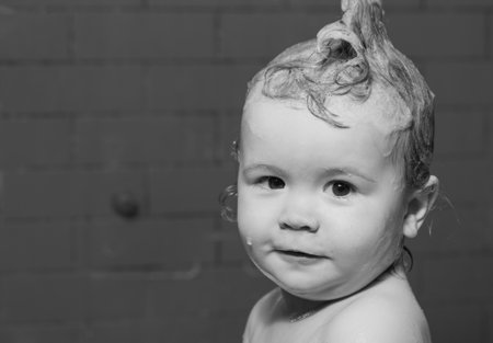 Little child in a bathtub. Little baby child is washing her hair in bath.の写真素材
