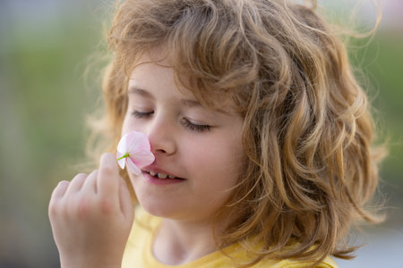 Kids smelling summer flower, closeup face. Funny child face close up. Kids head portrait. Close up faces kid. Funny kids face. Portrait cute boy. Head shoot kids portrait outdoor. Kid enjoying nature.の写真素材