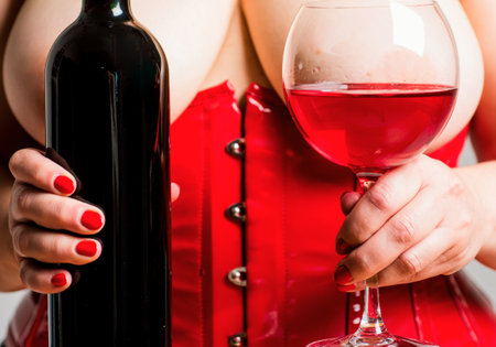Red wine in bra between boobs. Woman Plus Size posing with glass of wine. XXL big size. Beautiful girl shows her gorgeous Breasts. wine list for the restaurant menu. Woman in red holding wine glass.の写真素材