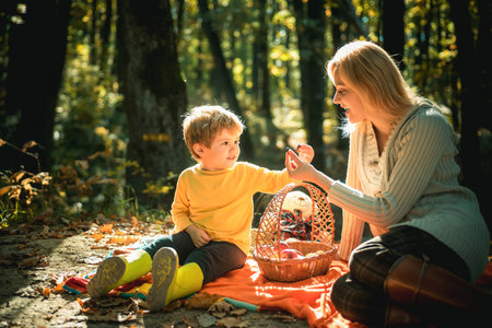 Teaching son healthy nutrition. Having snack picnic hike. Happy childhood. Mom and kid boy relaxing while hiking forest. Family picnic. Mother pretty woman and little son relaxing forest picnicの写真素材
